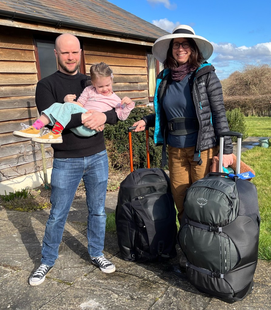 John and Stephanie standing outside with two suitcases